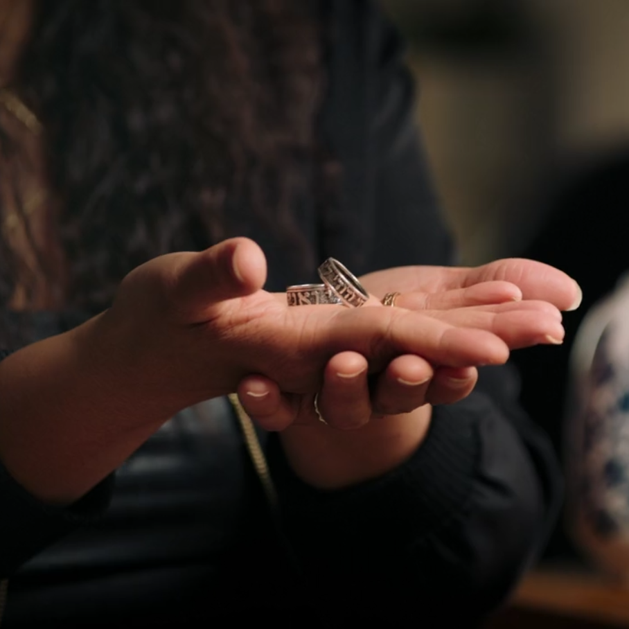 Dani Rocca-Herbert holds two honor rings, one made for men