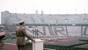 Hitler stands before a crowd at the opening ceremony of the Olympics. (Colorized)